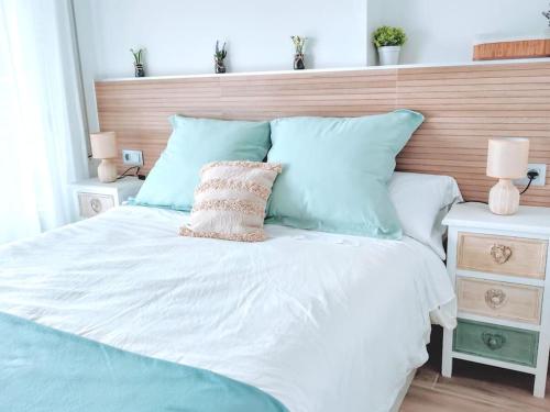 a bedroom with a white bed with blue pillows at Arrecife Beach in La Pineda