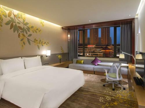 a hotel room with a large bed and a couch at Hilton Garden Inn Foshan in Foshan