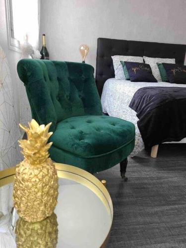 une chambre avec une chaise verte et un ananas sur une table dans l'établissement AppartStudio « You & Me in Champagne », à Épernay