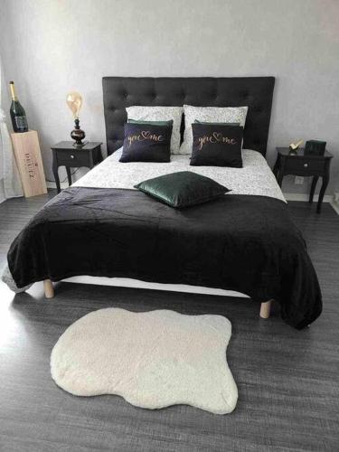 - un grand lit avec une couverture et des oreillers noirs dans l'établissement AppartStudio « You & Me in Champagne », à Épernay