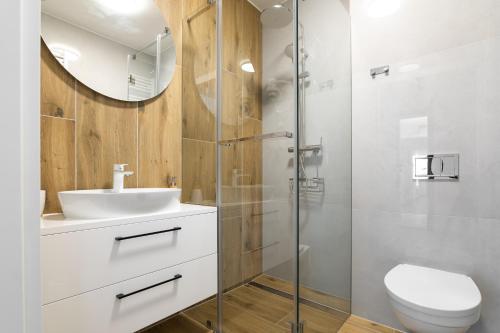 a bathroom with a sink and a toilet and a mirror at SOLEK Apartamenty i pokoje gościnne in Mielno