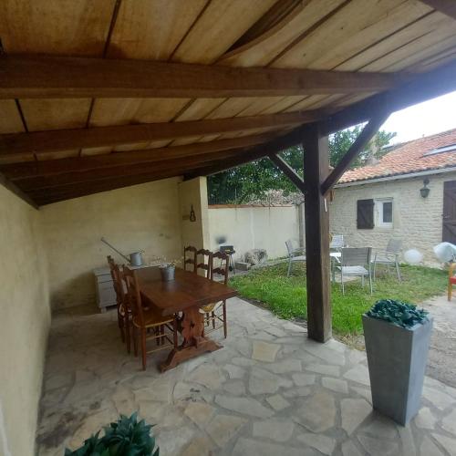 un patio con pérgola de madera, mesa y sillas en Maison de charme, raffinée dans village historique, en Vervant