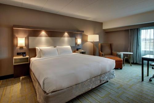 a hotel room with a large bed and a chair at Doubletree By Hilton Mt. Vernon in Mount Vernon