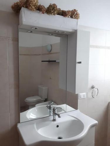 uma casa de banho com um lavatório branco e um espelho. em Casa Assunta em Corvara