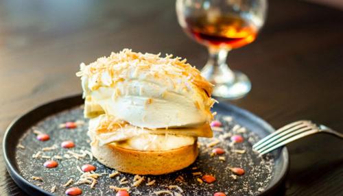 a piece of cake on a plate with a glass of wine at The Desmond Hotel Malvern, a DoubleTree by Hilton in Malvern