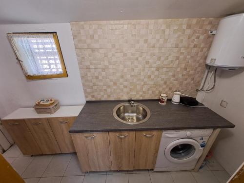 y baño con lavabo y lavadora. en Olive cabin - Kuća maslina i mira u Đenovićima!, en Herceg-Novi