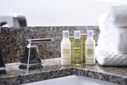 three bottles of moisturizers sitting on a bathroom sink at The Desmond Hotel Malvern, a DoubleTree by Hilton in Malvern