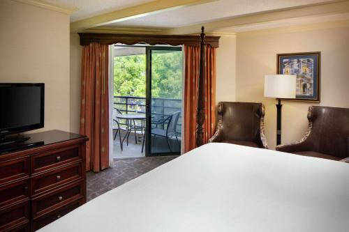 a bedroom with a bed and a television and a balcony at The Desmond Hotel Malvern, a DoubleTree by Hilton in Malvern