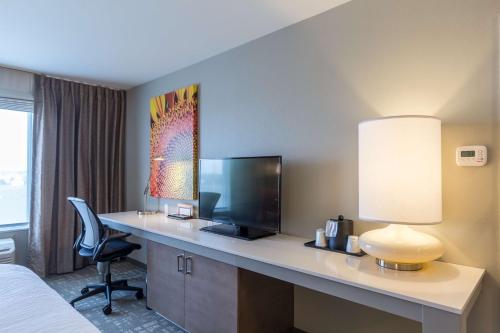 a hotel room with a desk with a television and a bed at Hilton Garden Inn Salina in Salina