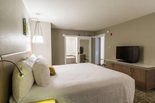 a bedroom with a white bed and a flat screen tv at Hilton Garden Inn Salina in Salina