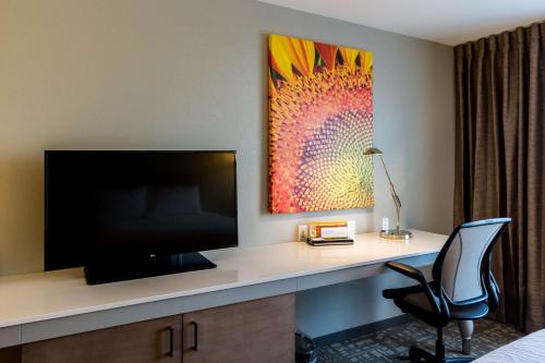 a desk with a television and a chair in a hotel room at Hilton Garden Inn Salina in Salina