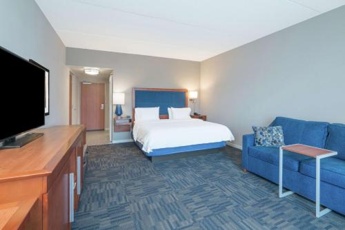 Habitación de hotel con cama y sofá azul en Hampton Inn & Suites Newburgh Stewart Airport, NY, en Newburgh