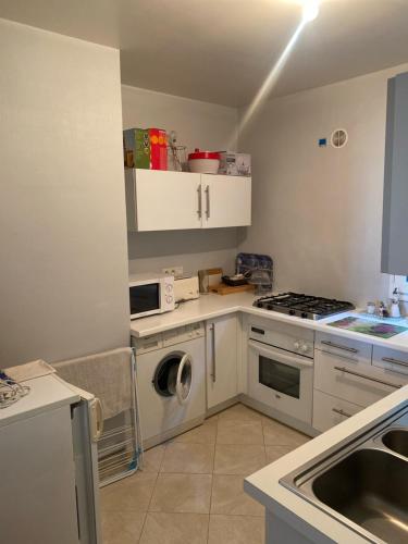 eine Küche mit weißen Schränken, einer Waschmaschine und einem Trockner in der Unterkunft Appartement port de pêche in Granville