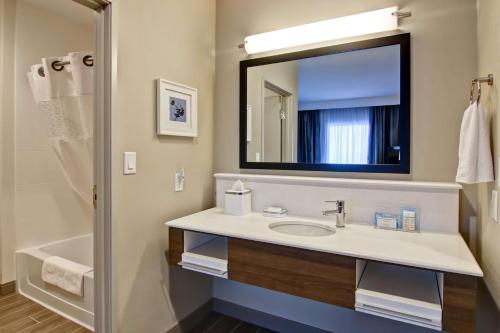 a bathroom with a sink and a mirror at Hampton Inn & Suites by Hilton Grande Prairie in Grande Prairie