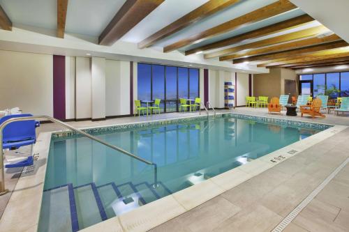a pool in a hotel room with chairs and tables at Home2 Suites By Hilton Pittsburgh Area Beaver Valley in Monaca