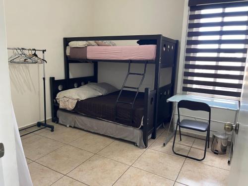 a room with two bunk beds with a desk and a chair at Departamento para familias in Mazatlán