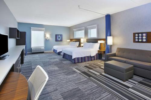 Habitación de hotel con 2 camas y sofá en Home2 Suites By Hilton Pittsburgh Area Beaver Valley, en Monaca