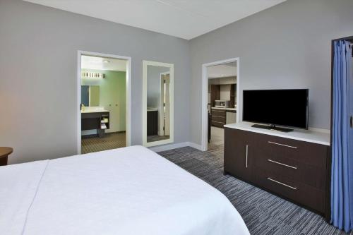a hotel room with a bed and a flat screen tv at Home2 Suites By Hilton Pittsburgh Area Beaver Valley in Monaca
