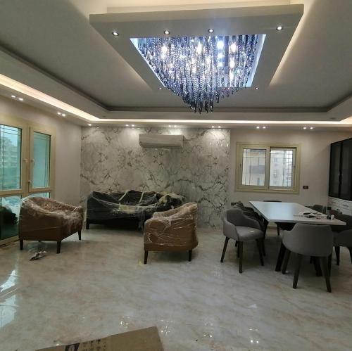 a living room with a chandelier and a table and chairs at elite department in Kafr al Muşayliḩah