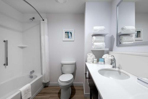a white bathroom with a toilet and a tub and a sink at Hampton Inn & Suites West Melbourne-Palm Bay Road in Melbourne