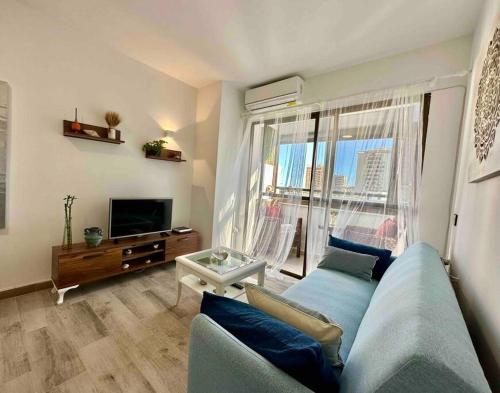 a living room with a blue couch and a large window at Apartamento en Aguadulce sur in Aguadulce