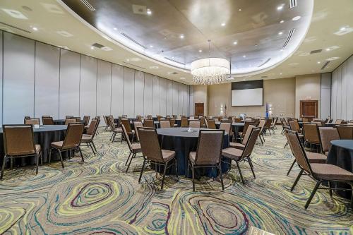a conference room with tables and chairs and a screen at Hilton Garden Inn Edmond/Oklahoma City North in Edmond