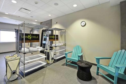 a room with two blue chairs and a clock at Home2 Suites by Hilton Brownsville in Brownsville