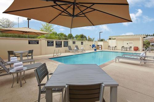 Hampton Inn & Suites Sacramento at CSUS في سكرامنتو: مسبح بالطاولات والكراسي ومظلة