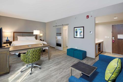 サクラメントにあるHampton Inn & Suites Sacramento at CSUSのベッドとデスクが備わるホテルルームです。