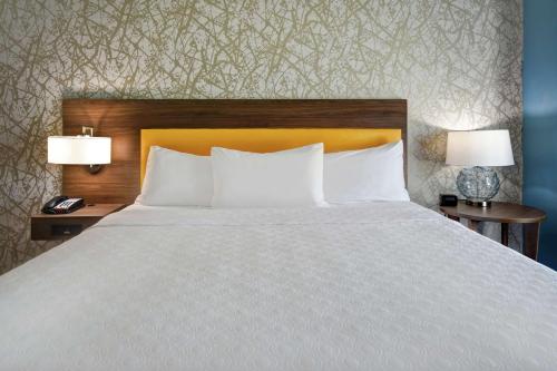 a bed with white pillows and two tables with lamps at Home2 Suites By Hilton Oklahoma City Airport in Oklahoma City