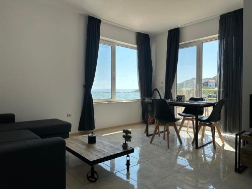 25m FROM THE BEACH!! Luxury Sea Paradise Apartment في كافارنا: غرفة معيشة مع طاولة وكراسي ونوافذ
