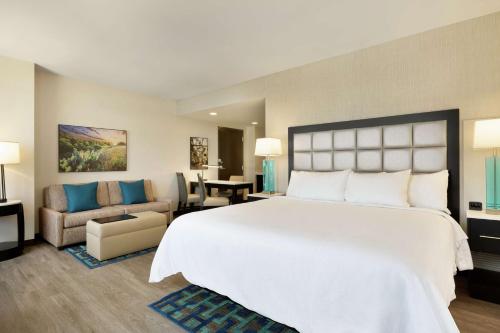 ein Schlafzimmer mit einem großen weißen Bett und ein Wohnzimmer in der Unterkunft Embassy Suites By Hilton San Antonio Landmark in San Antonio