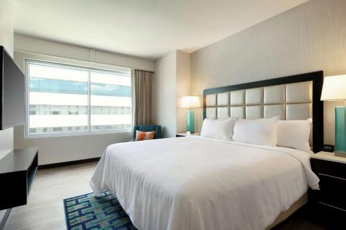 a hotel room with a large bed and a window at Embassy Suites By Hilton San Antonio Landmark in San Antonio