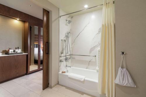 a bathroom with a tub and a shower with a shower curtain at The Porter Portland, Curio Collection By Hilton in Portland