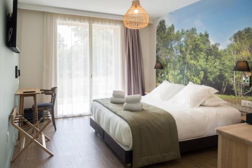 um quarto com uma cama e uma grande janela em Hôtel et Cottages Domaine Du Marquenterre em Saint-Quentin-en-Tourmont