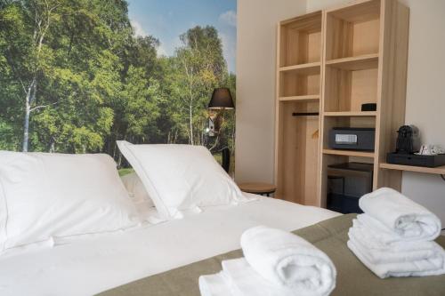 - une chambre avec un lit blanc et des serviettes dans l'établissement Hôtel et Cottages Domaine Du Marquenterre, à Saint-Quentin-en-Tourmont