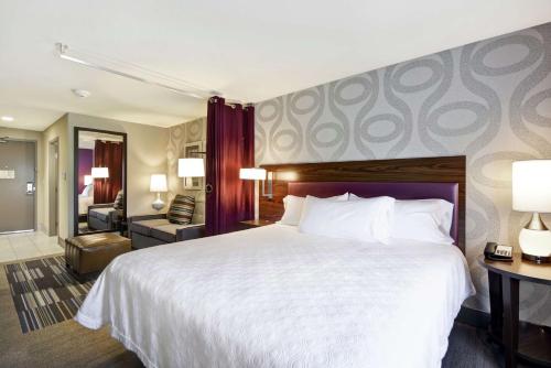 a hotel room with a large bed and a living room at Home2 Suites by Hilton KCI Airport in Kansas City