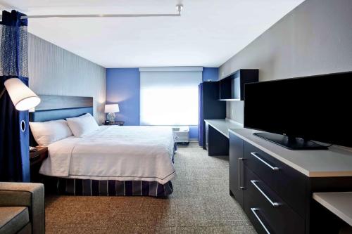 a hotel room with a bed and a flat screen tv at Home2 Suites by Hilton Atlanta Norcross in Norcross
