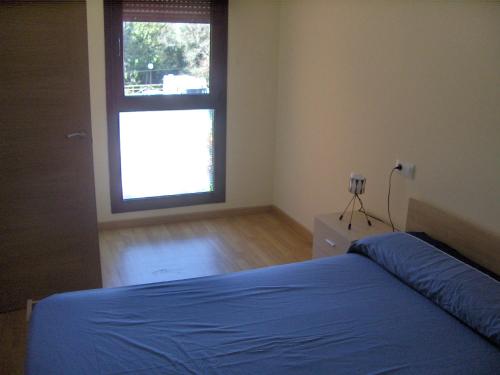 una camera con un letto blu e una finestra di Pisos alquiler Panes, Asturias a Panes