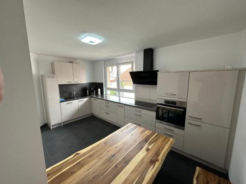 a kitchen with white cabinets and a wooden table at Deluxe Appartement in Graben-Neudorf