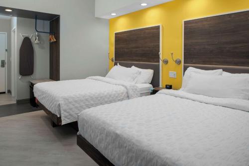 Cette chambre d'hôtel dispose de 2 lits et d'un mur jaune. dans l'établissement Tru By Hilton Farmville Va, à Farmville