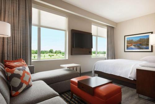 a hotel room with a bed and a couch at Embassy Suites By Hilton Noblesville Indianapolis Conv Ctr in Noblesville