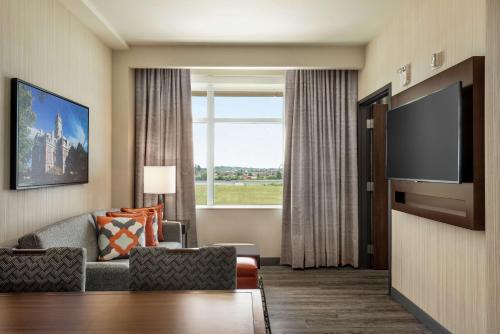 a living room with a flat screen tv and a couch at Embassy Suites By Hilton Noblesville Indianapolis Conv Ctr in Noblesville