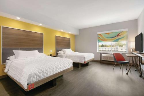 a hotel room with two beds and a desk and a television at Tru By Hilton Williamsville Buffalo Airport in Williamsville