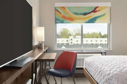 um quarto com uma cama e uma secretária com uma televisão em Tru By Hilton Williamsville Buffalo Airport em Williamsville