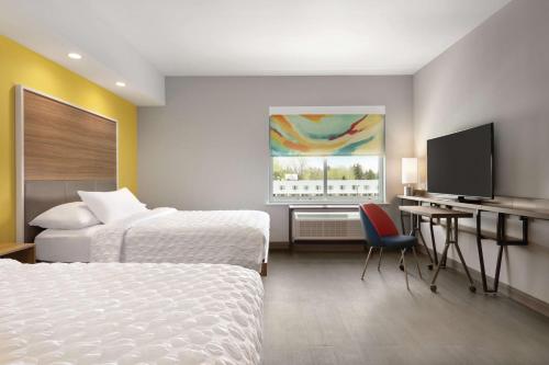 a hotel room with two beds and a desk and a television at Tru By Hilton Williamsville Buffalo Airport in Williamsville
