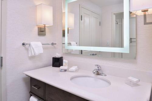a bathroom with a sink and a mirror at Homewood Suites Des Moines Airport in Des Moines