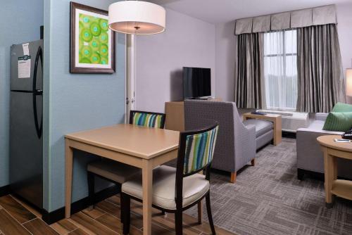 a small living room with a table and a kitchen at Homewood Suites Des Moines Airport in Des Moines