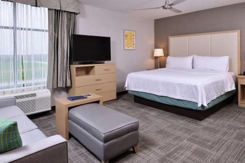 a hotel room with a bed and a flat screen tv at Homewood Suites Des Moines Airport in Des Moines