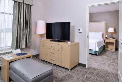 a hotel room with a bed and a flat screen tv at Homewood Suites Des Moines Airport in Des Moines